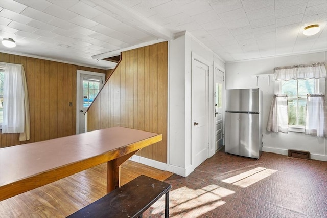 unfurnished dining area featuring crown molding and wood walls