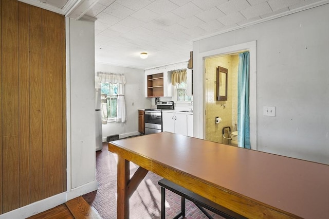 kitchen with white cabinets, electric stove, crown molding, and sink