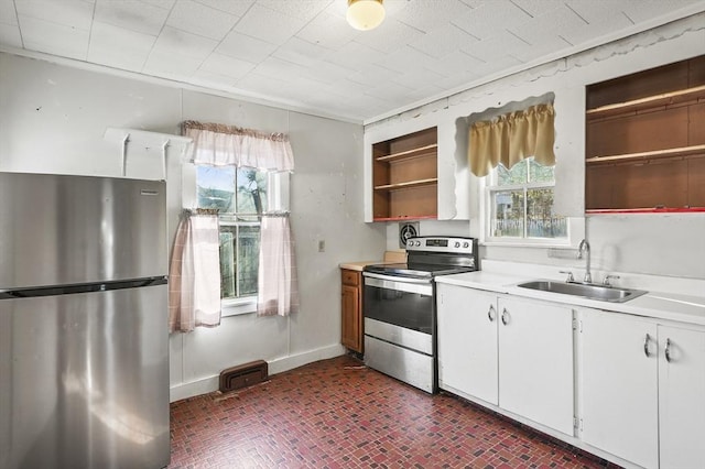 kitchen with appliances with stainless steel finishes, white cabinetry, plenty of natural light, and sink