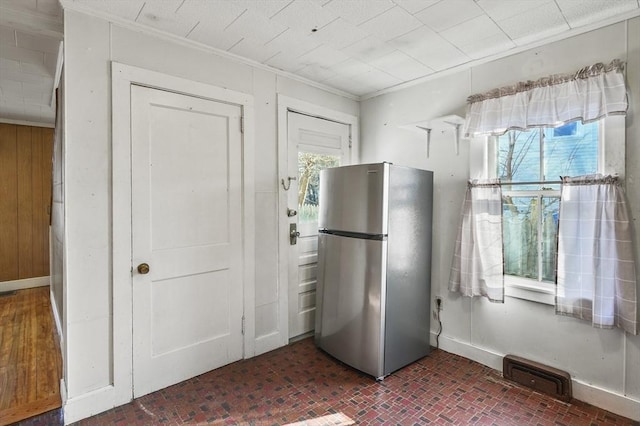 kitchen with stainless steel refrigerator, plenty of natural light, and crown molding