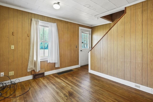 foyer entrance featuring ornamental molding, wooden walls, and wood-type flooring