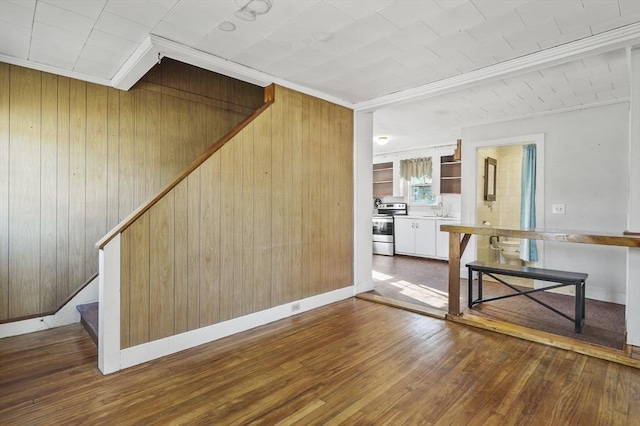 interior space featuring sink, ornamental molding, wooden walls, and hardwood / wood-style flooring