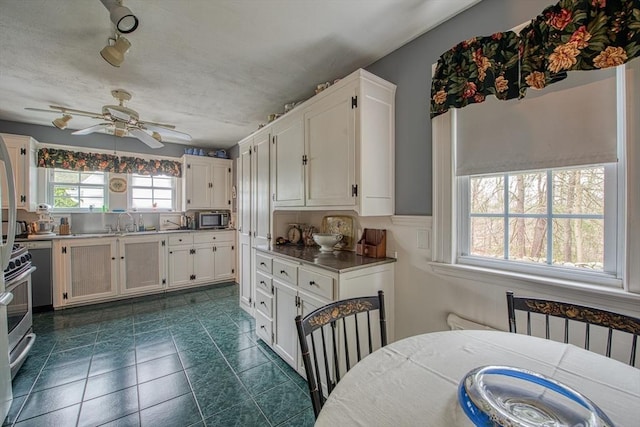 27 Carrlyn Rd, Brockton, MA 02301 - kitchen featuring a sink, a ceiling fan, stainless steel microwave, white cabinetry, and dark tile patterned flooring