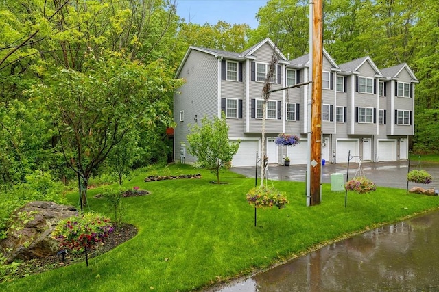 63 Shrine Ave Unit 1, West Boylston, MA 01583 - view of front facade featuring a garage, driveway, a water view, a front lawn, and view of scattered trees