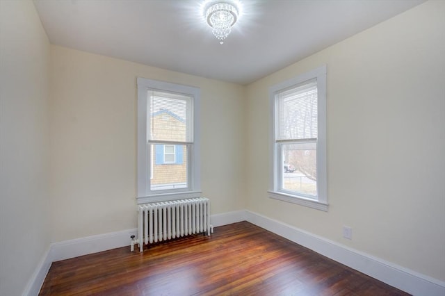 spare room with dark wood-type flooring, radiator heating unit, a wealth of natural light, and baseboards