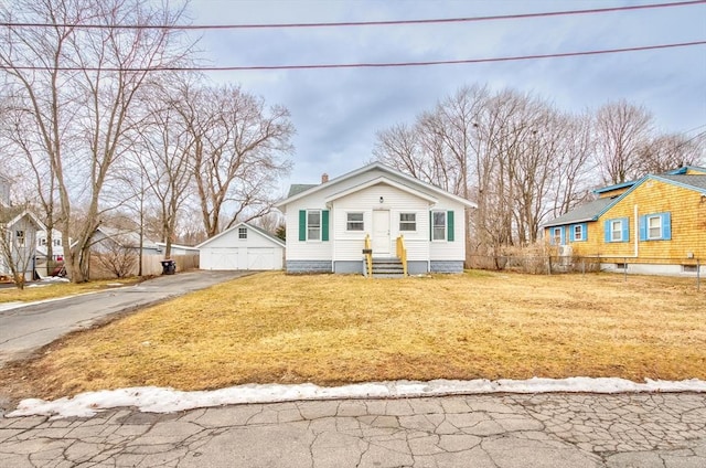 bungalow-style house featuring entry steps, a chimney, a front lawn, and an outbuilding