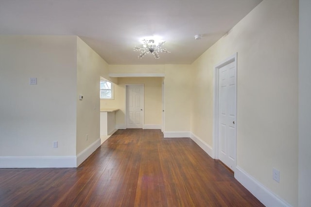 unfurnished room featuring baseboards, a chandelier, and wood finished floors