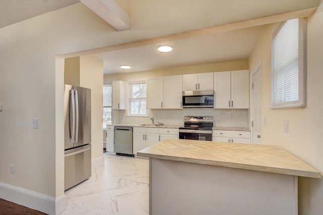 kitchen with marble finish floor, stainless steel appliances, white cabinets, a sink, and butcher block countertops