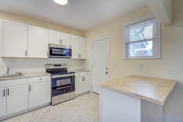 kitchen with marble finish floor, appliances with stainless steel finishes, a sink, and white cabinets
