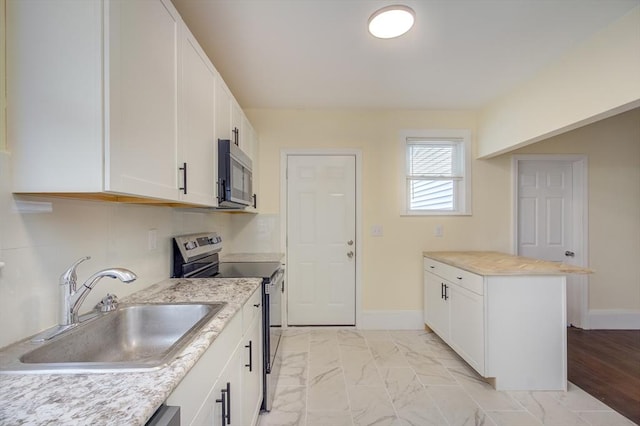 kitchen with appliances with stainless steel finishes, marble finish floor, light countertops, white cabinetry, and a sink