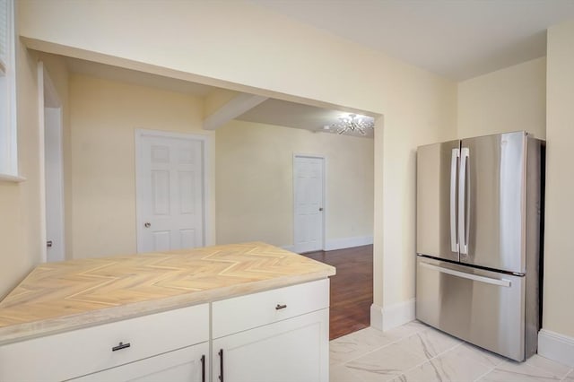 kitchen featuring baseboards, butcher block countertops, white cabinetry, and freestanding refrigerator
