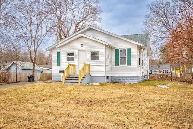 bungalow-style house featuring a front lawn, roof with shingles, and fence