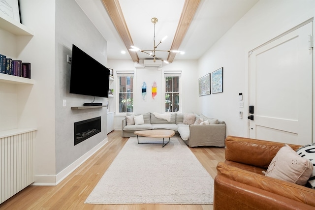 living room featuring beamed ceiling, light hardwood / wood-style flooring, a wall unit AC, and an inviting chandelier