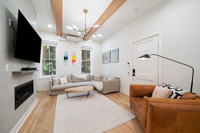 living room featuring beam ceiling, a chandelier, light hardwood / wood-style flooring, and a wall mounted air conditioner