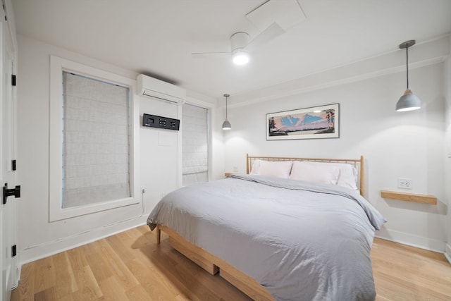 bedroom with light hardwood / wood-style floors, a wall mounted AC, and ceiling fan