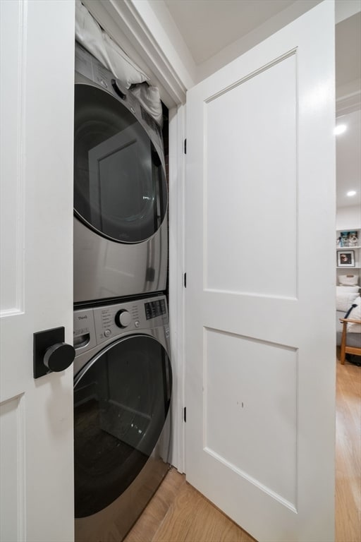 laundry room featuring light hardwood / wood-style flooring and stacked washer / dryer