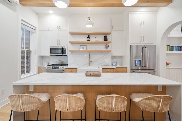 kitchen with a center island, white cabinetry, stainless steel appliances, and light wood-type flooring