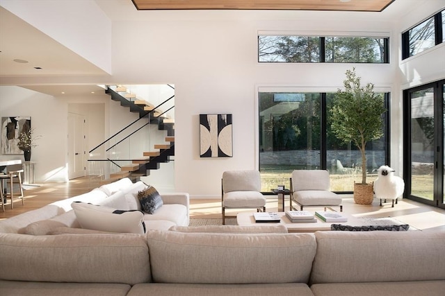 living room featuring light wood-type flooring and a towering ceiling