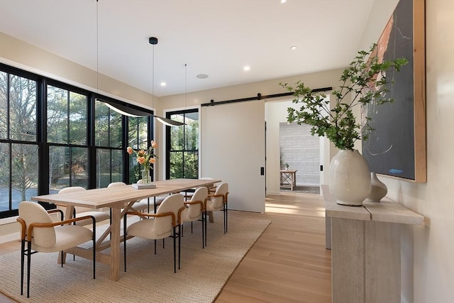 dining space with a barn door and light hardwood / wood-style flooring