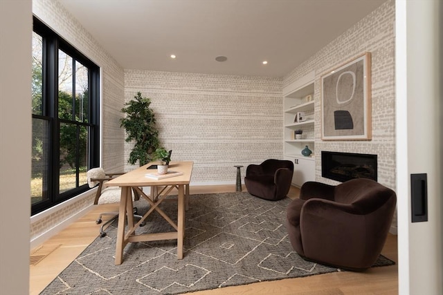 interior space featuring a large fireplace, hardwood / wood-style flooring, built in features, and a wealth of natural light