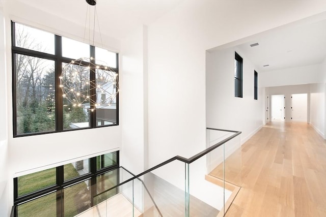 corridor featuring a chandelier, plenty of natural light, and light hardwood / wood-style floors