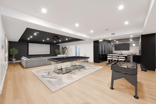 rec room with light wood-type flooring, sink, billiards, and a tray ceiling