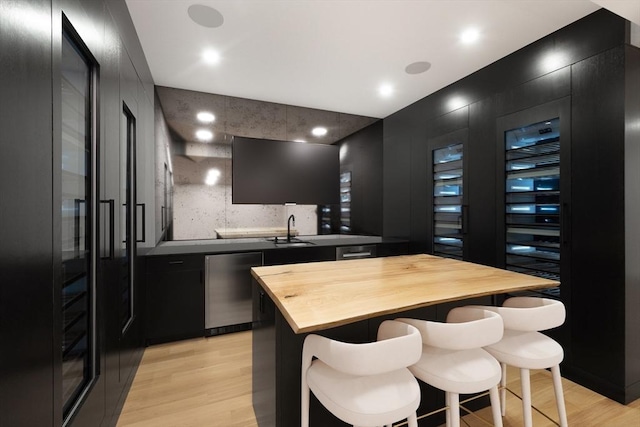 bar featuring backsplash, dishwasher, light wood-type flooring, and sink