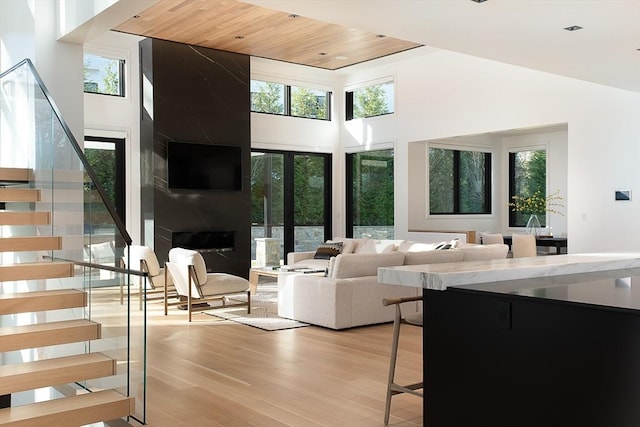 living room with a high ceiling, light hardwood / wood-style flooring, and wood ceiling