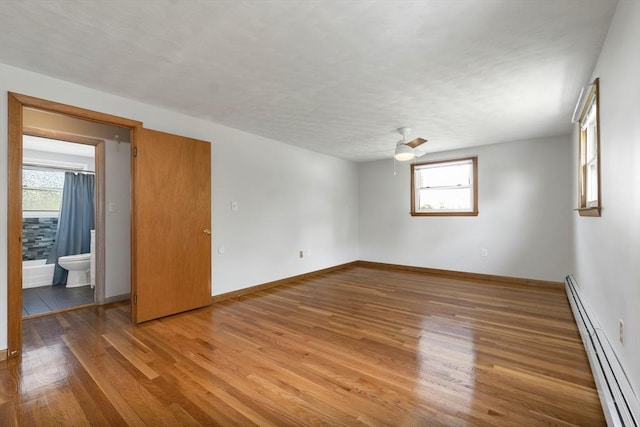 21 Gile St, Haverhill, MA 01830 - empty room featuring baseboard heating, plenty of natural light, wood finished floors, and baseboards