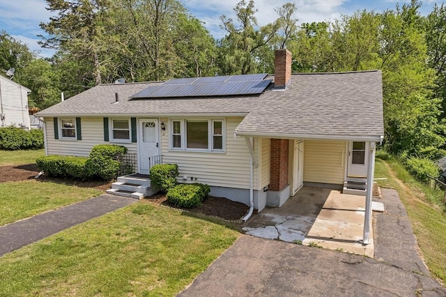 21 Gile St, Haverhill, MA 01830 - view of front facade with driveway, a front yard, roof with shingles, a chimney, and roof mounted solar panels