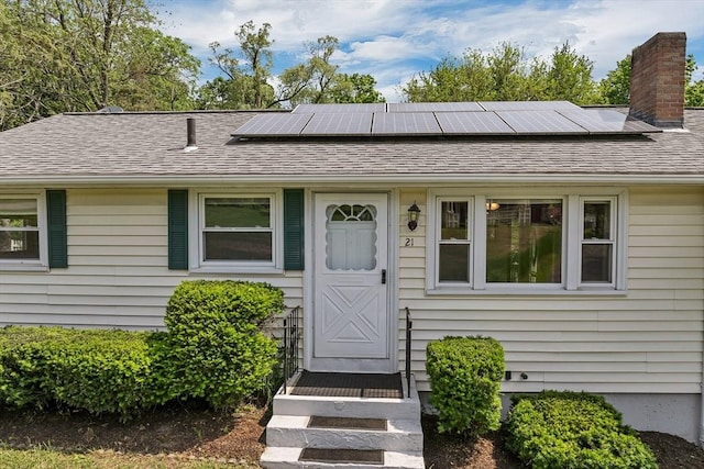 21 Gile St, Haverhill, MA 01830 - view of front facade with a chimney, roof mounted solar panels, and a shingled roof