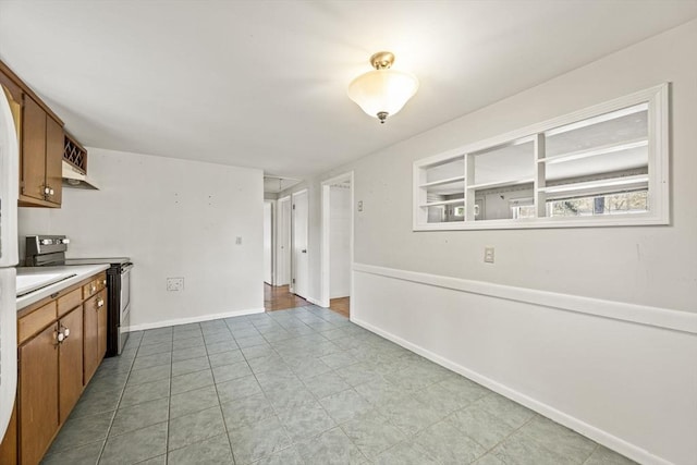 kitchen with stainless steel electric range, brown cabinetry, light countertops, and baseboards