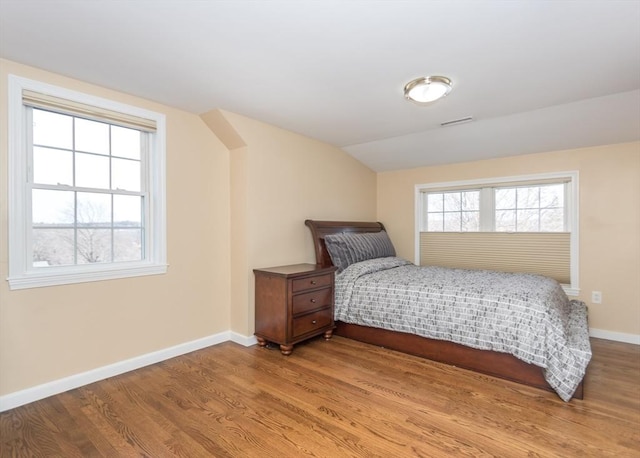 bedroom featuring baseboards, lofted ceiling, and wood finished floors