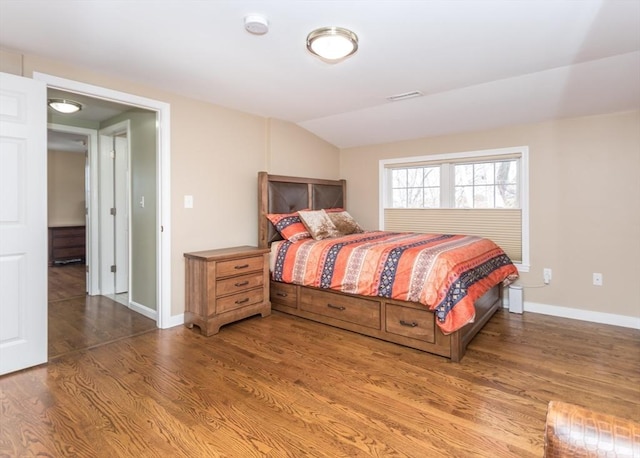 bedroom featuring visible vents, baseboards, lofted ceiling, and wood finished floors