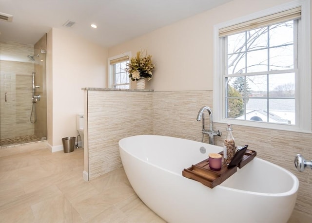 bathroom with visible vents, a shower stall, tile walls, and a freestanding tub