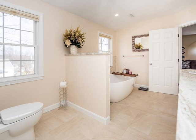 full bathroom featuring toilet, recessed lighting, tile patterned flooring, baseboards, and a freestanding bath