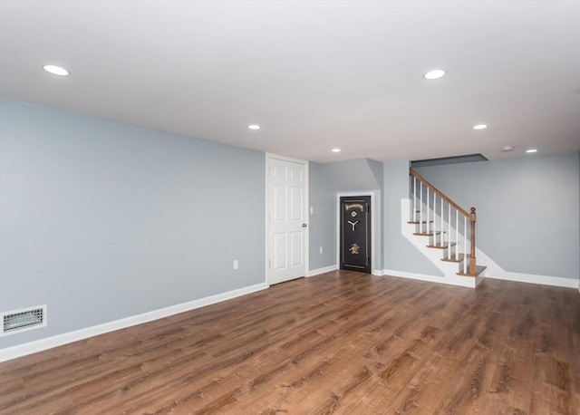 unfurnished living room featuring visible vents, stairway, baseboards, and wood finished floors