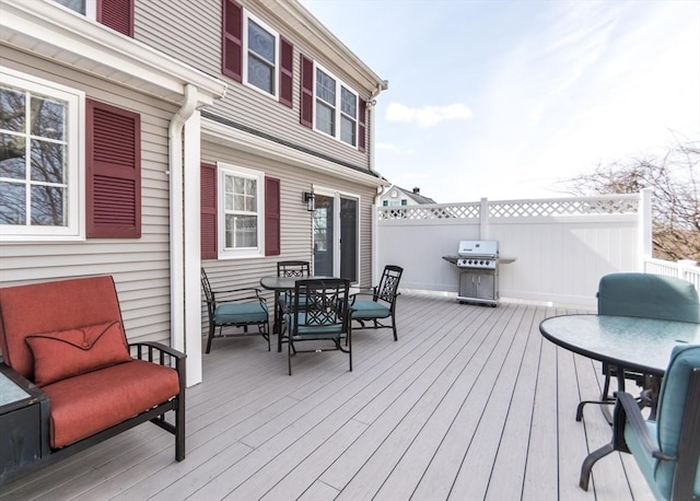 deck with a grill, outdoor dining area, and fence