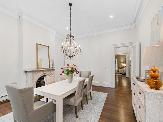 dining space with a premium fireplace, dark hardwood / wood-style flooring, ornamental molding, and an inviting chandelier