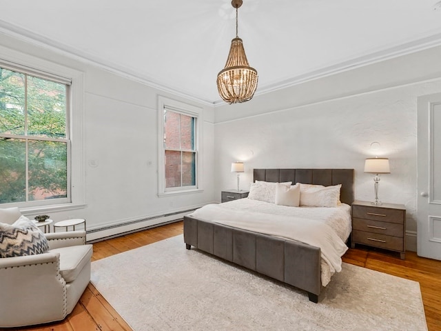 bedroom with crown molding, light hardwood / wood-style flooring, and a baseboard radiator