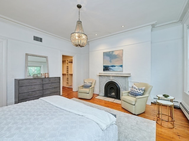 bedroom featuring a walk in closet, crown molding, hardwood / wood-style flooring, an inviting chandelier, and a closet