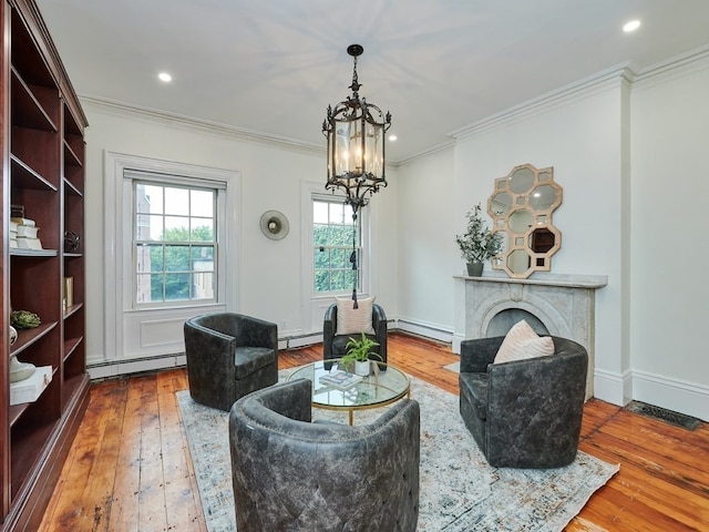 sitting room with hardwood / wood-style flooring, a baseboard heating unit, ornamental molding, and an inviting chandelier