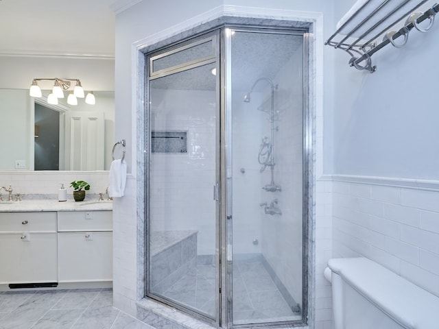 bathroom with vanity, a shower with door, toilet, ornamental molding, and tile walls