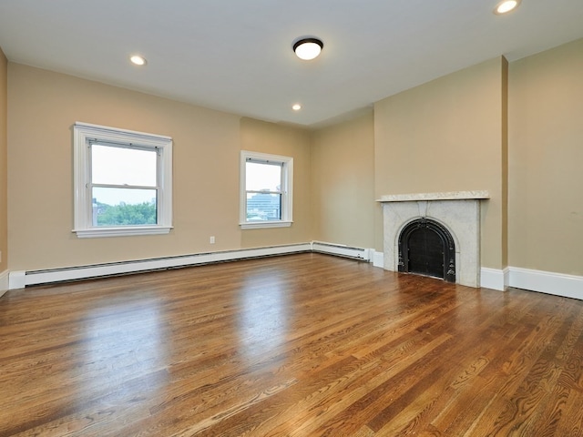 unfurnished living room featuring a fireplace, hardwood / wood-style floors, and a baseboard heating unit