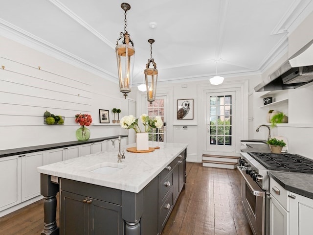 kitchen with dark wood-type flooring, dark stone counters, sink, stainless steel range, and decorative light fixtures