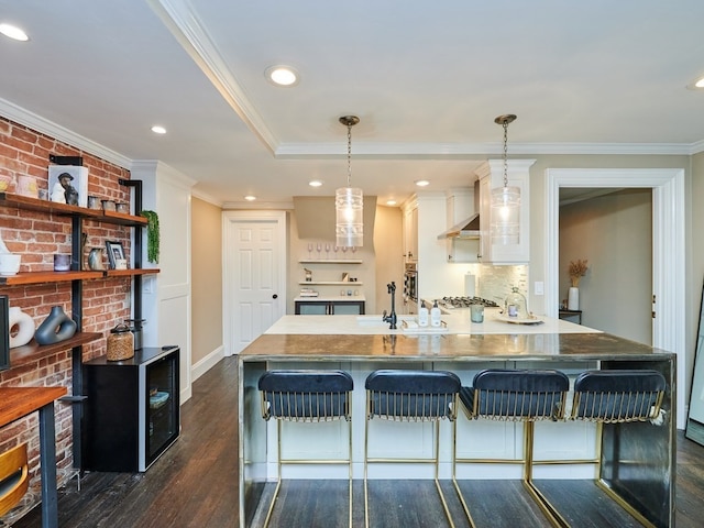 kitchen featuring white cabinetry, hanging light fixtures, a kitchen breakfast bar, dark hardwood / wood-style floors, and crown molding