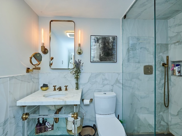 bathroom featuring toilet, sink, tiled shower, and tile walls