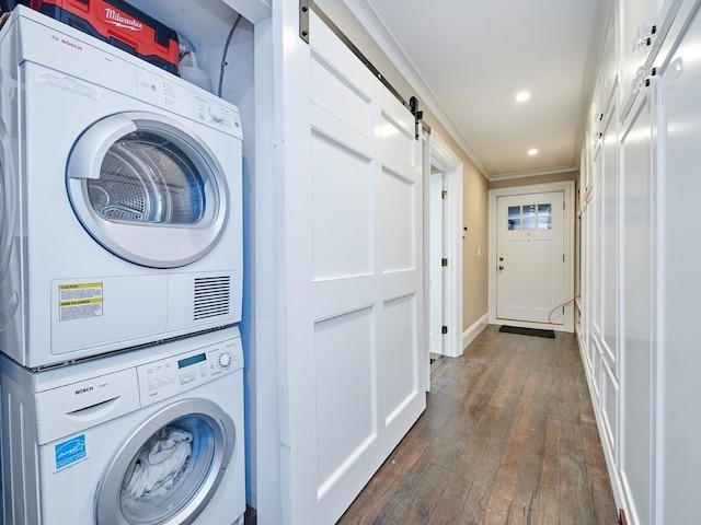 washroom with a barn door, dark hardwood / wood-style floors, stacked washer and clothes dryer, and ornamental molding