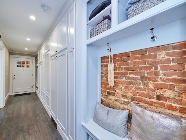 mudroom with dark hardwood / wood-style floors and brick wall