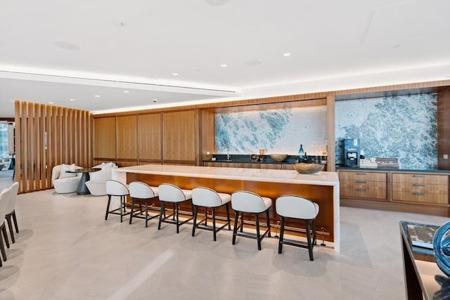 kitchen featuring brown cabinetry, a large island, a kitchen bar, and modern cabinets